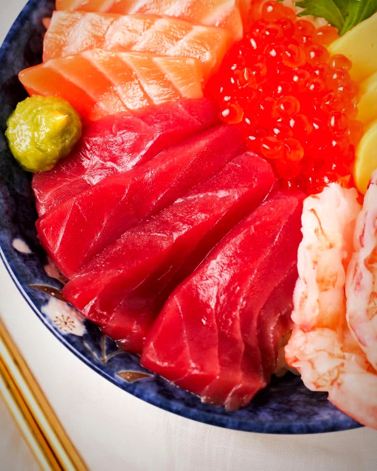 A loaded Daisuki sushi bowl with fresh fish, avocado, and rice.